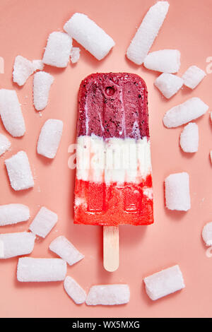 Petits fruits multicolores de la crème glacée sur un bâton avec des cubes de glace sur un arrière-plan Couleur de l'année 2019 de coraux vivants Pantone. Vue d'en haut Banque D'Images