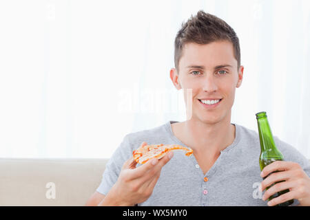 A smiling man comme il mange des pizzas et des bières Banque D'Images