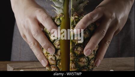 Vue en gros plan. Woman's hands hold deux pièces d'ananas juteux organique naturelle douce sur un fond de bois. Banque D'Images