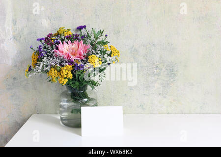 Vase en verre coloré avec de beaux bouquet de lisianthus, tansies et aster fleurs. Grunge vieux mur arrière-plan. Mariage, anniversaire féminin maquette des lieux Banque D'Images