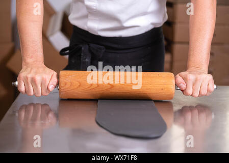 À l'aide de rouleau à pâtisserie préparation du fondant pour la décoration de gâteau. Banque D'Images