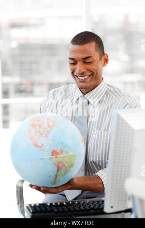 Smiling businessman holding globe aterrestrial au bureau Banque D'Images