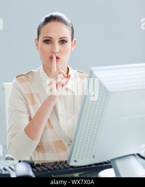 Attractive businesswoman at a computer pour demander le silence dans le bureau Banque D'Images