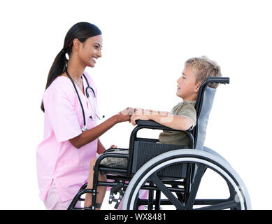 Ciute petit garçon dans un fauteuil roulant en train de discuter avec son médecin sur un fond blanc. Banque D'Images