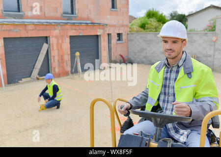 Construction Worker driving dumper sur place Banque D'Images