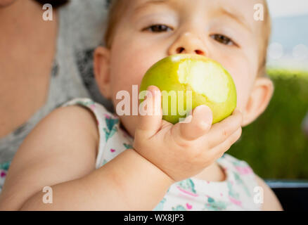 Little baby eating apple, closeup portrait, concept de soins de santé et de nutrition de l'enfant en bonne santé Banque D'Images