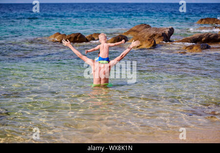 Bébé garçon sur les épaules du père at beach Banque D'Images