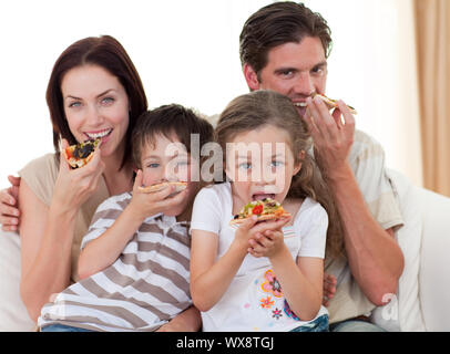 Happy Family eating pizza sur le canapé Banque D'Images