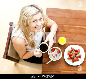 Cute femme ayant un petit-déjeuner sain dans un salon Banque D'Images