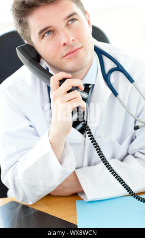 Beau mâle médecin parler au téléphone dans son bureau Banque D'Images