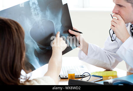 Attractive doctor de l'analyse d'une x-ray avec une patiente Banque D'Images