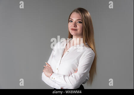 Portrait d'une jeune femme séduisante aux cheveux blonds sur un fond gris neutre. Banque D'Images
