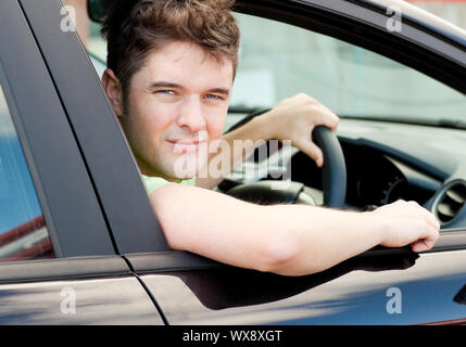 Heureux les jeunes conducteur assis dans sa voiture et en regardant par la fenêtre Banque D'Images