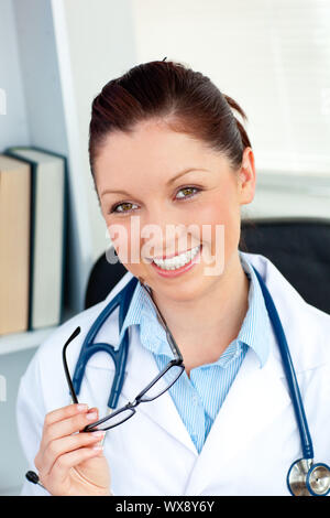 Happy female doctor smiling at the camera assis dans son bureau Banque D'Images