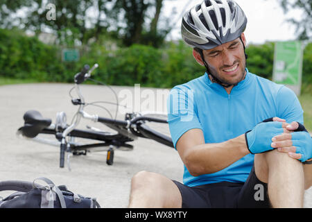 Le cycliste est tombé de vélo avec genou blessé Banque D'Images