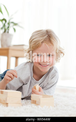 Adorable petit Garçon jouant avec les dominos se trouvant sur le plancher de la salle de séjour Banque D'Images