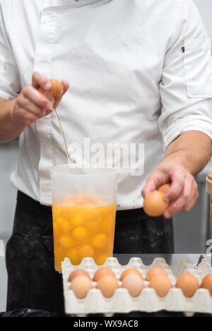 Chef pâtissier casser des œufs pour préparer le gâteau Banque D'Images