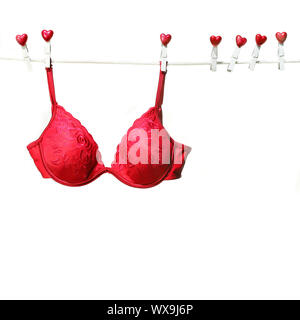 Soutien-gorge rouge fantaisie accroché sur corde avec fond blanc Banque D'Images