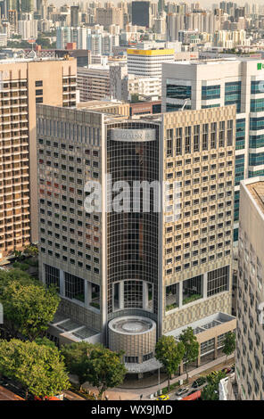 Singapour - Mars 21, 2019 : tourné sur des centaines de gratte-ciel avec pas de ciel. Centré sur Carlton Hotel. Feuillage vert et du trafic de rue en dessous. Banque D'Images