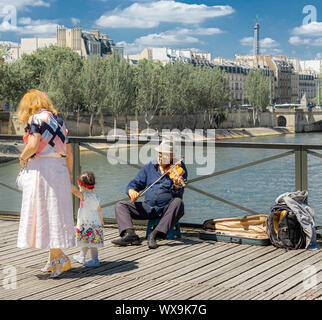 Paris, France - le 4 juillet 2017 : Vieil homme sur un tabouret à jouer du violon comme par les touristes de passage pour obtenir des conseils sur le Pont des Arts pont sur la Seine à Paris. Banque D'Images