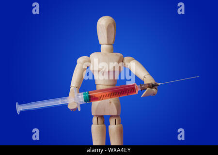Jouet en bois figure avec la seringue sur bleu Banque D'Images
