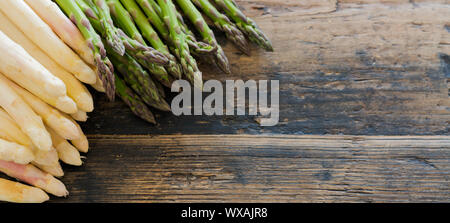 Produits frais bio asperges vertes et blanches sur une vieille table en bois brun rustique Banque D'Images