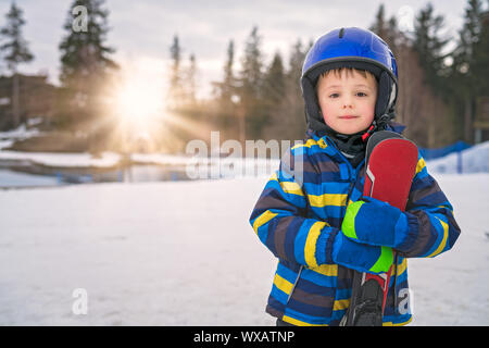 Little Boy holding ses skis en hiver Banque D'Images