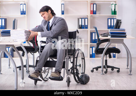 Beau jeune employé en fauteuil roulant travaillant au bureau Banque D'Images