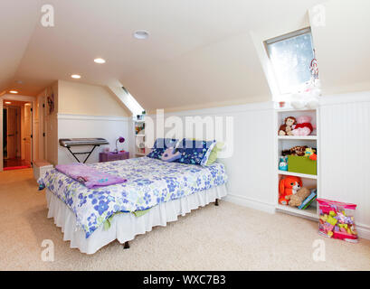 Girl chambre avec plafond voûté et grenier tapis beige avec des jouets. Banque D'Images