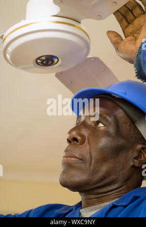 African American Construction Worker, bricoleur, menuisier, électricien, fixation ventilateur de plafond Banque D'Images