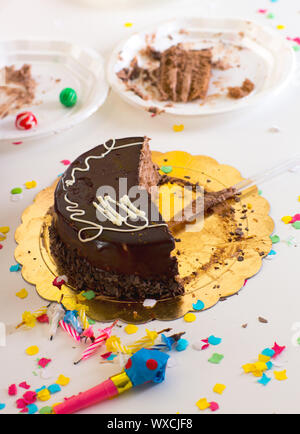 Après la fin de fête d'anniversaire d'enfant avec la moitié des tranches de gâteau au chocolat et confettis Banque D'Images