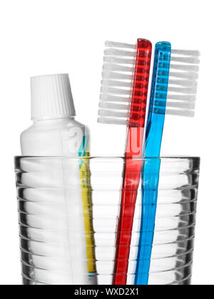 Deux brosses à dents et un tube de dentifrice dans un verre sur fond blanc. Banque D'Images