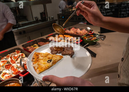 Les droits de cueillette à la main l'alimentation dans son assiette en buffet restaurant Banque D'Images