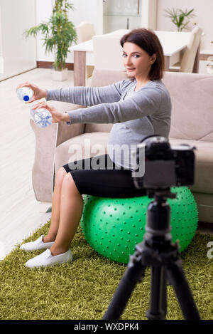 Femme enceinte blogger faisant des exercices physiques Banque D'Images