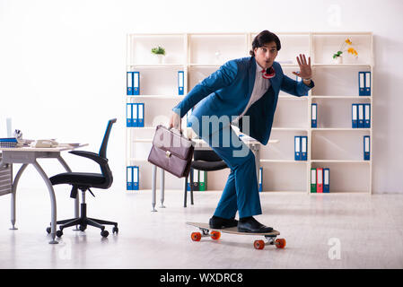 Young handsome businessman avec longboard au bureau Banque D'Images