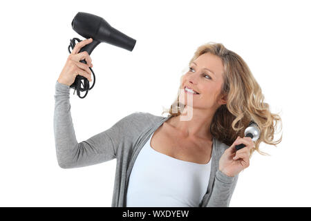 Femme aux cheveux longs à l'aide d'un sèche-cheveux et une grande brosse ronde Banque D'Images