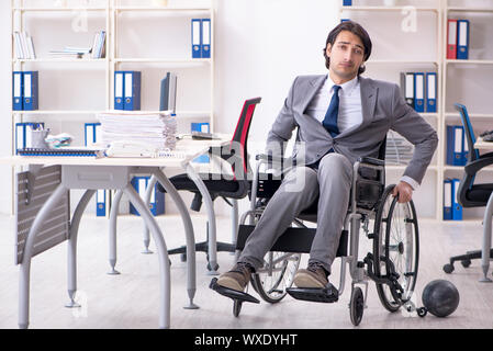 Beau jeune employé en fauteuil roulant travaillant au bureau Banque D'Images