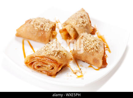 Crêpes roulées avec mousse au caramel et noix. On white Banque D'Images