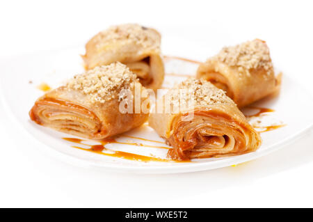 Crêpes roulées avec mousse au caramel et noix. On white Banque D'Images