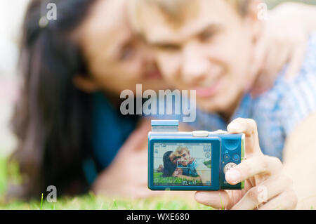 Jeune couple heureux émotionnel prendre photo sur l'herbe au parc de la ville Banque D'Images