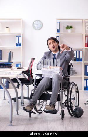 Beau jeune employé en fauteuil roulant travaillant au bureau Banque D'Images