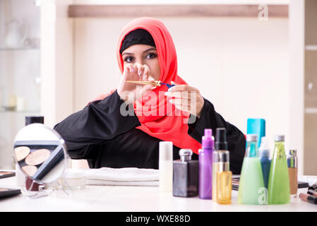 Belle femme en hijab applying make-up Banque D'Images