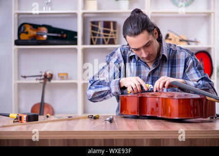 Beau jeune réparateur réparation violoncelle Banque D'Images