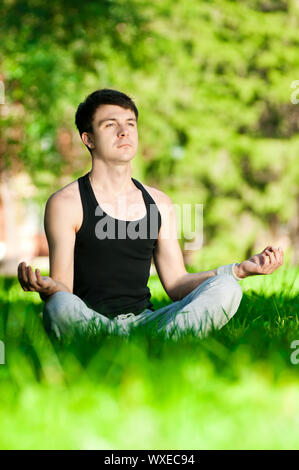 Un jeune homme faisant du yoga dans le vert du parc Banque D'Images