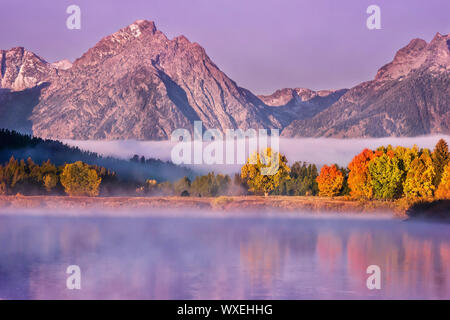 Paysage d'automne à l'aube, avec feuillage coloré reflète dans l'eau, et la Misty Teton Mountains en arrière-plan. Parc National de Grand Teton. Banque D'Images