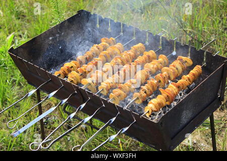 Shashliks à partir de morceaux de pommes de terre et bacon. La cuisson des pommes de terre et bacon en feu. Pique-nique à la nature. Déjeuner barbecue. Brochettes de pommes de terre marinées Banque D'Images