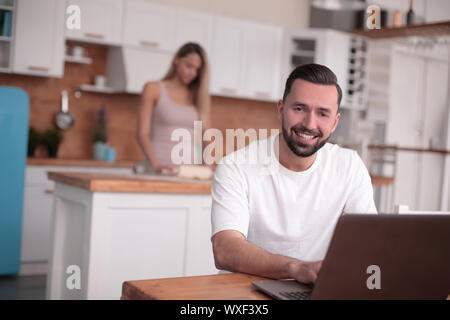 Jeune homme utilise en cuisine accueil ordinateur portable Banque D'Images