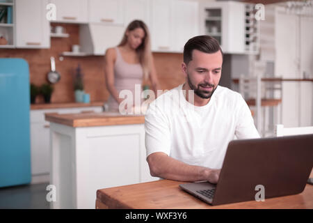 Jeune homme utilise en cuisine accueil ordinateur portable Banque D'Images