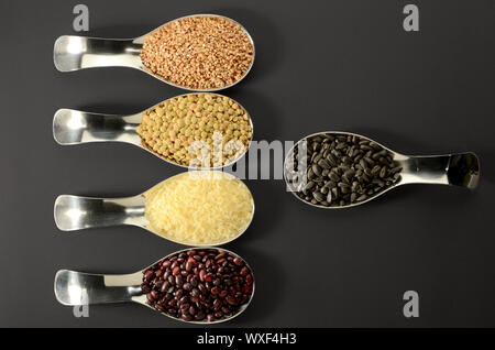 Les graines de sarrasin riz Haricots Lentilles en cuillère SUR FOND NOIR Banque D'Images
