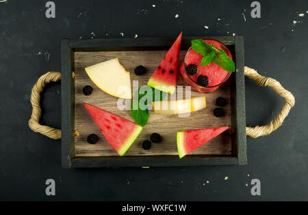 La pastèque Melon mûres de MENTHE ET UN VERRE DE JUS DANS LA BOÎTE DANS L'ARRIÈRE-PLAN. RIPE MELON MELON JUTEUX AVEC BLACKBERR Banque D'Images